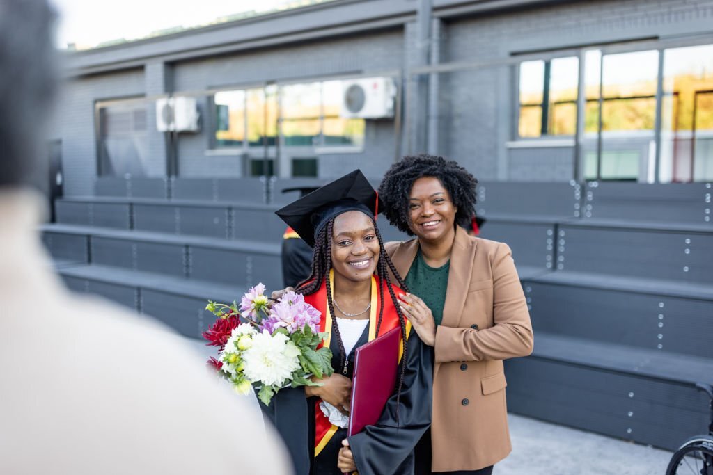 Graduation. Smiling Black woman hugging daughter